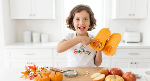 Child exploring butternut squash seeds and apples during a fall harvest kitchen STEM activity.