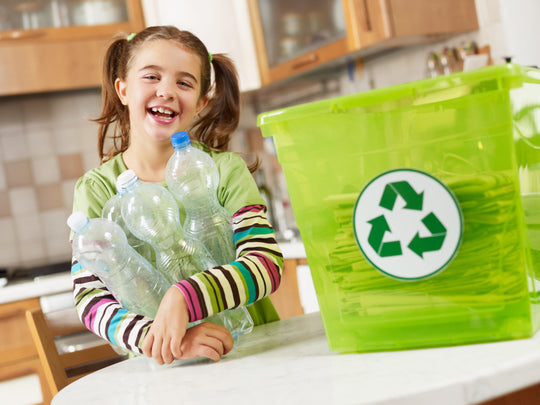 Girl,Looking,At,Camera,And,Holding,Plastic,Bottles,For,Recycling
